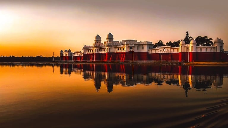 Red brick fortress with domed buildings reflected in calm water at golden sunset