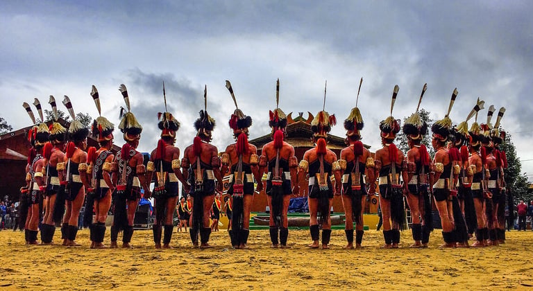 Large group of mounted soldiers in red and gold uniforms holding ceremonial spears, lined up in formation on a sandy field