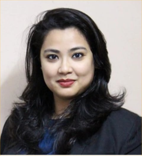 Professional headshot of a woman with long black hair, red lipstick, wearing a dark blazer over a blue top