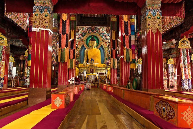 Interior of a Buddhist temple with a large golden Buddha statue in the center, surrounded by red columns and ornate decorations