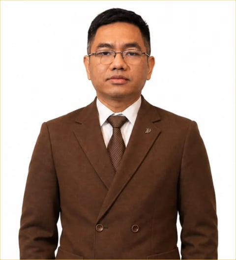 Professional headshot of an Asian man wearing glasses and a brown double-breasted blazer with tie against a white background