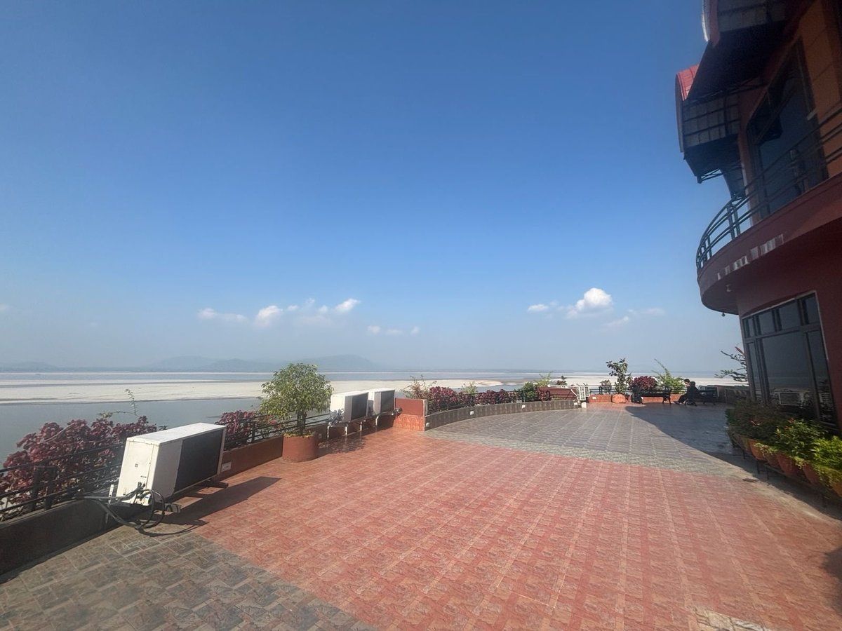 Rooftop terrace with red brick paving overlooking a wide river or waterway under clear blue sky