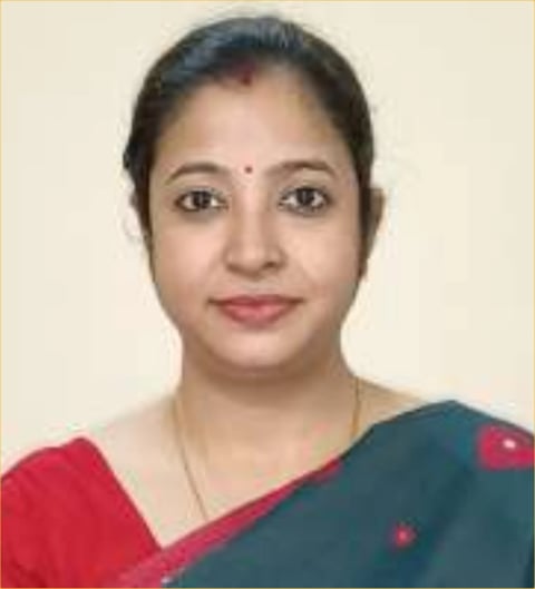 Portrait of a woman wearing a teal and red sari against a beige background, looking directly at camera
